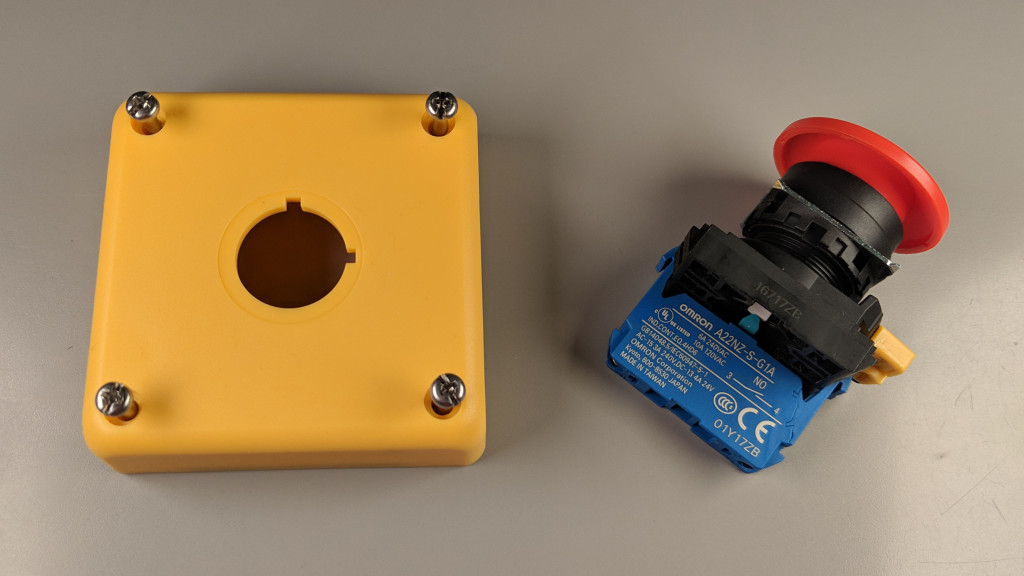 Raw materials. The lid of the enclosure and pushbutton switch with mushroom operator.
