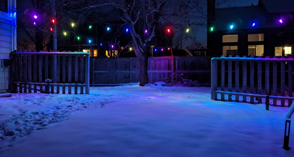 Two XMCOSY+ RGBW light strings hanging in my backyard over my snow-covered lawn.