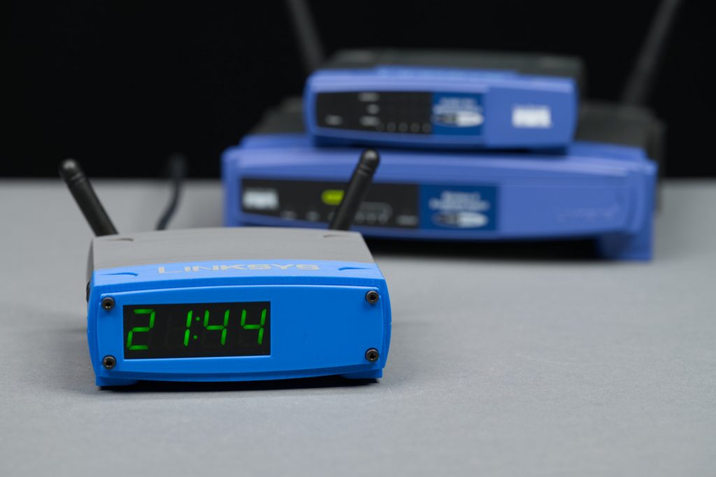 The completed clock in front of a 5-port switch and a wireless router.